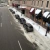 Cars parked on a a neighborhood street by a snow-covered sidewalk