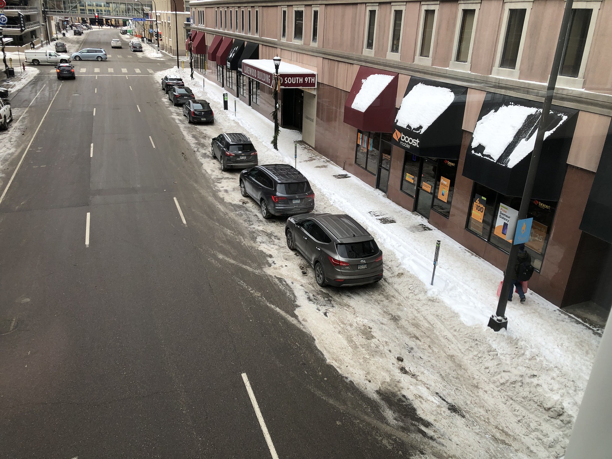 Cars parked on a a neighborhood street by a snow-covered sidewalk